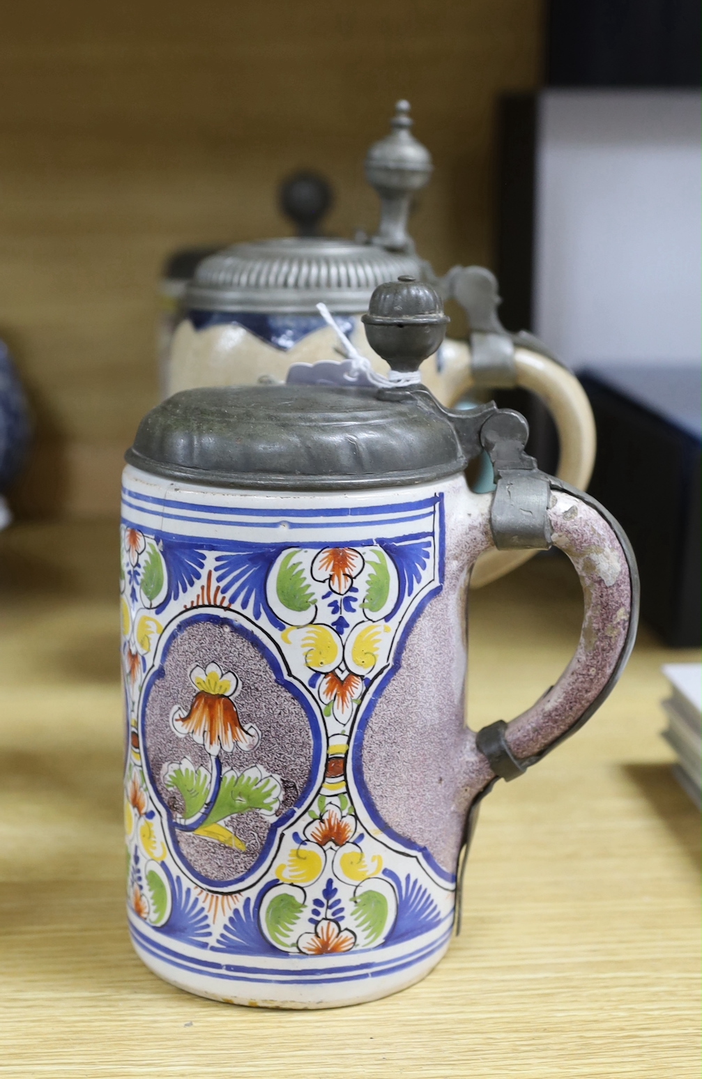 Four 18th century German faience lidded tankards and a salt glazed tankard, all with hinged pewter lids, tallest 25cm, (5)